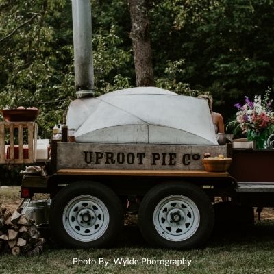 Mobile wood fired pizza oven for Uproot Pie Company with flowers on the side of the table. 