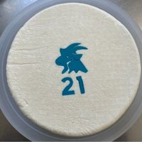 Wheel of hard goat cheese with blue imprint of a goat buck head and number 