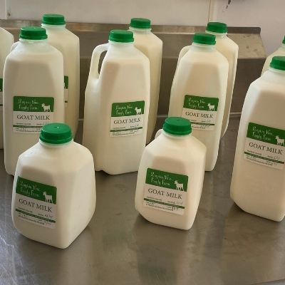 bottles of Pumpkin Vine Family Farm goat milk on a stainless steel table in the creamery