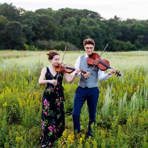 two people playing violin and viola in a field.