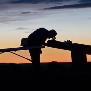 person looking into a high powered telescope at sunset.