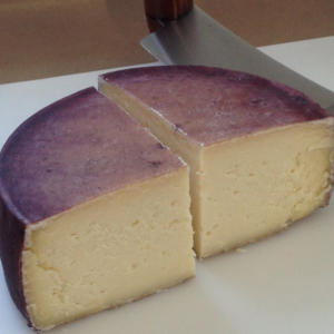 A wheel of Drunken Goat Cheese with a purple top made by Pumpkin Vine Family Farm in Somerville Maine. 
