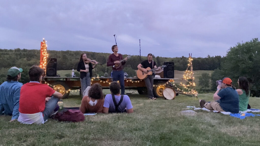 musicians playing with lights in the farm fields on a flatbed hay trailer.