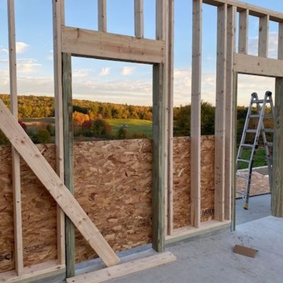 framed walls and foundation with fall trees in background.