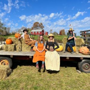 four people on a hay wagon dressed up as farmers